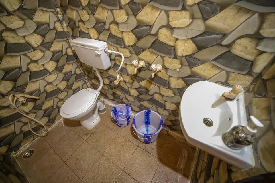 A bathroom with stone-effect wall tiles, a washbasin and buckets