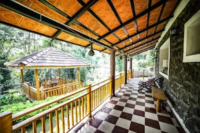 The Stone Villa’s covered verandah with a chequered floor, looking out to the wooden gazebo among the trees